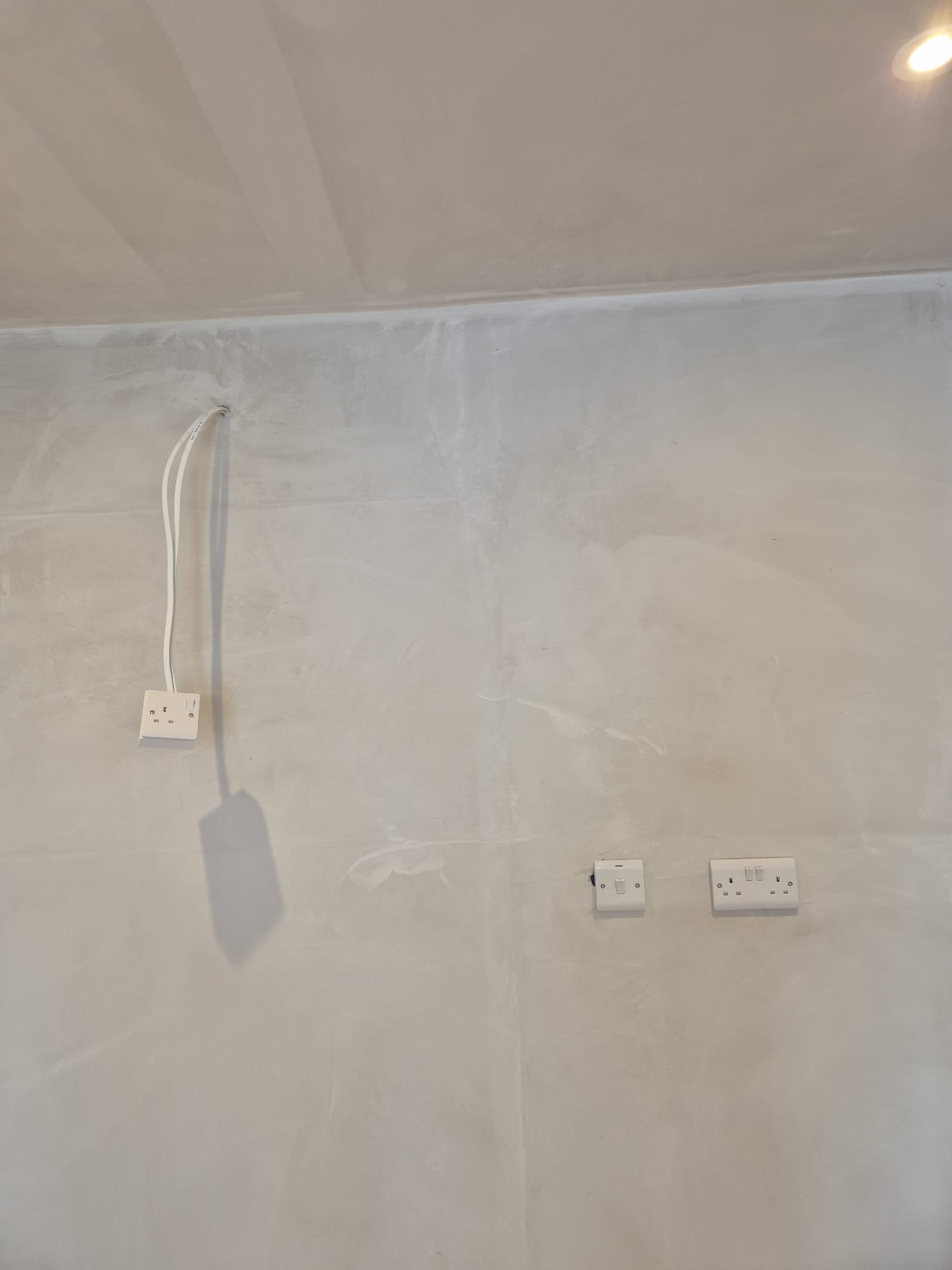 Sockets and switches set out on a newly plastered wall.