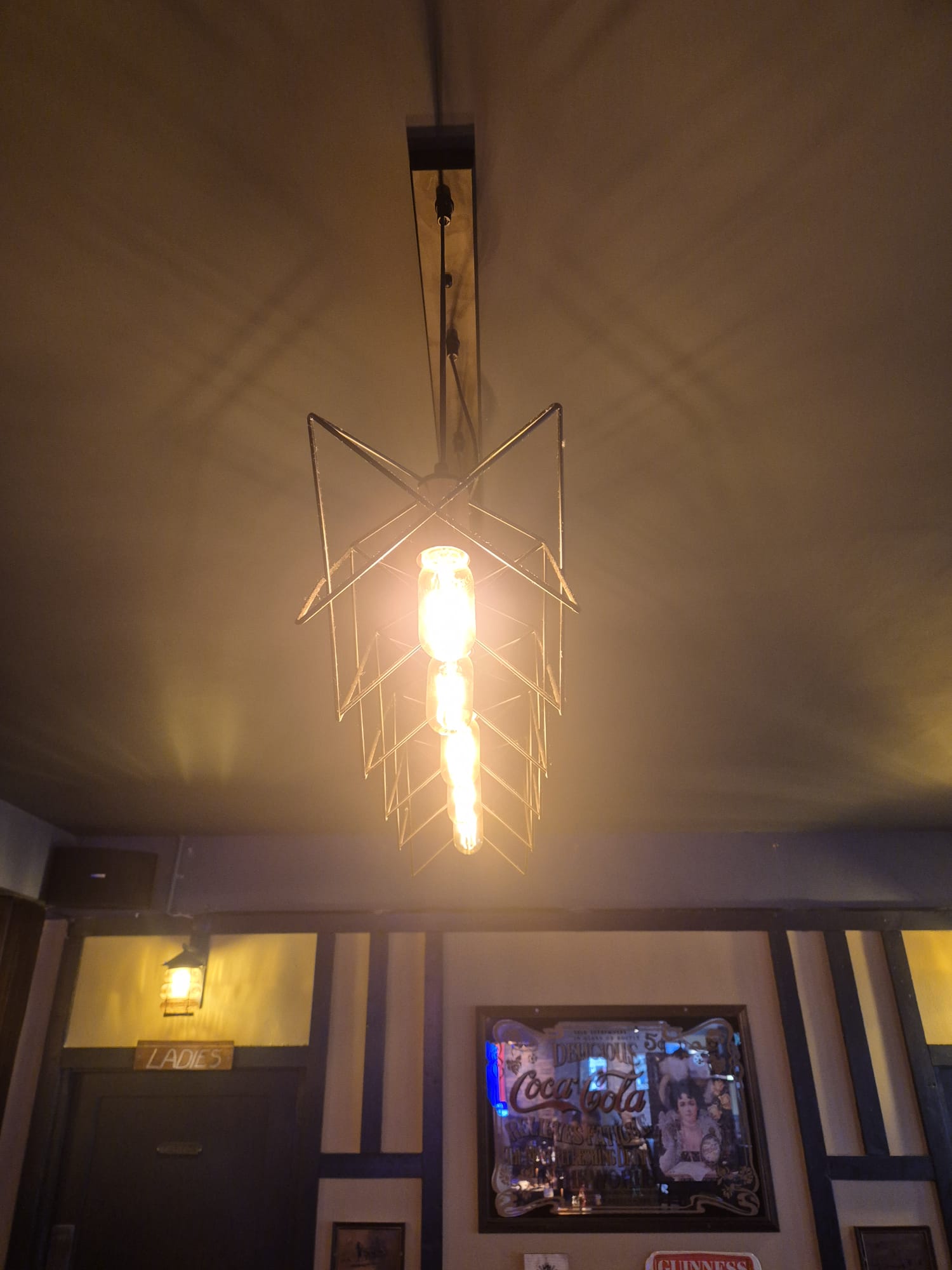 Cage pendant fitted over a bar with a filament lamp.
