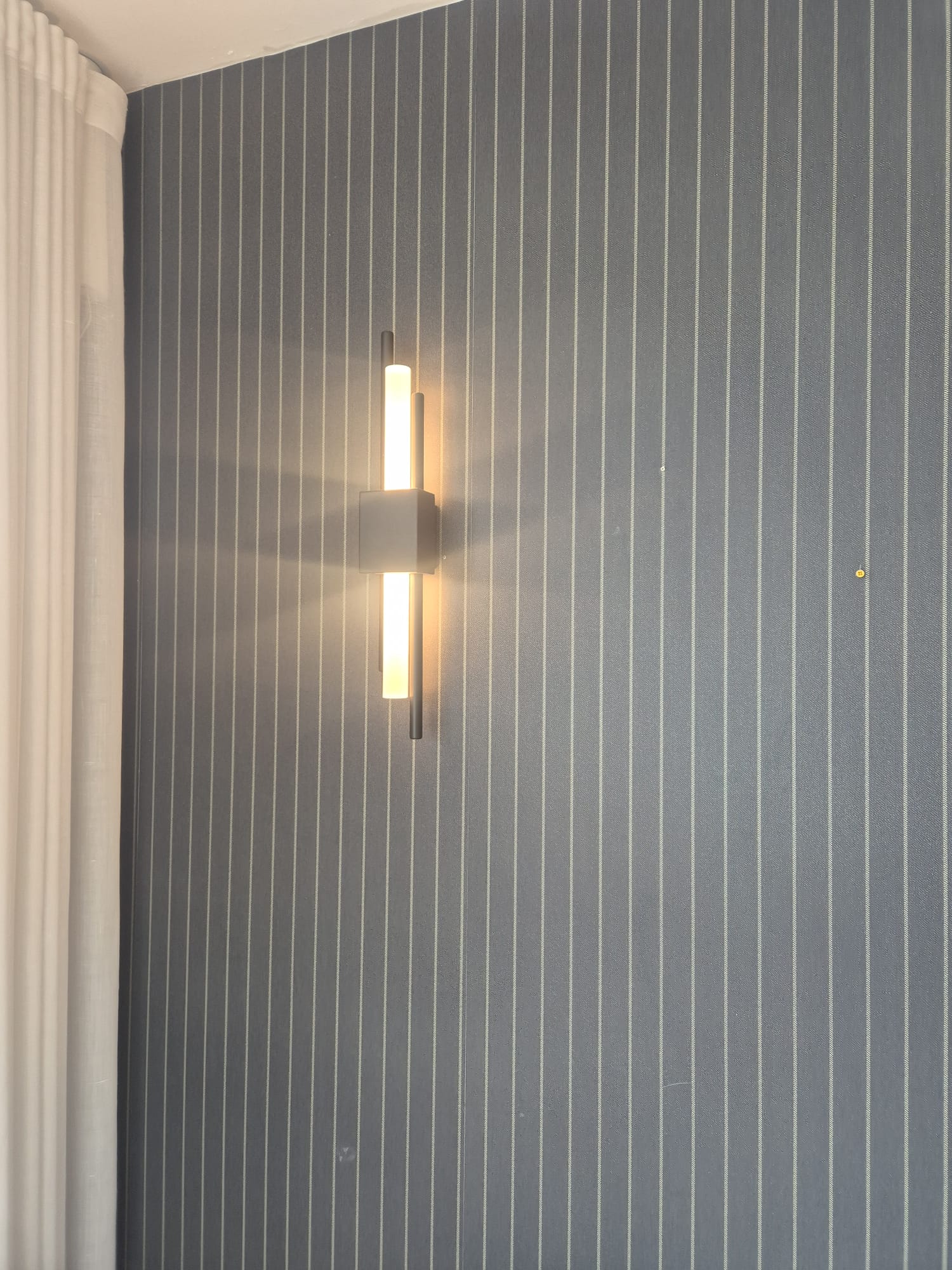 Up-and-down wall light fitted flush to a papered wall.